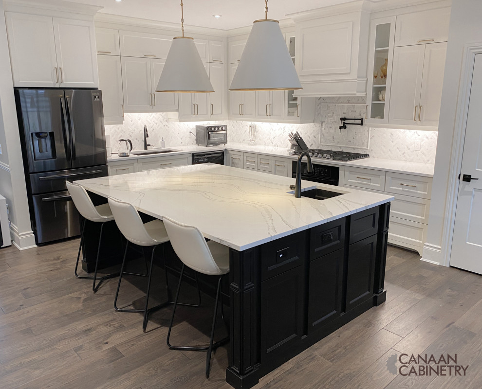 Example of a large transitional l-shaped eat-in kitchen design with an undermount sink, recessed-panel cabinets, white cabinets, quartz countertops, white backsplash, ceramic backsplash, black appliances, an island and white countertops