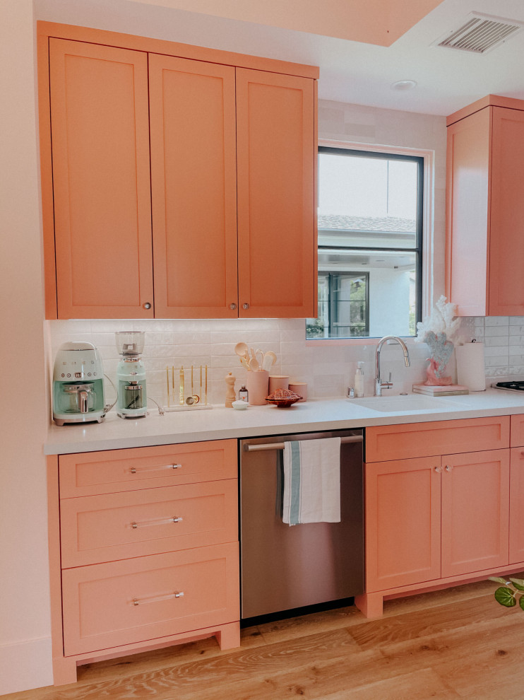 This is an example of a small tropical single-wall open plan kitchen in Los Angeles with shaker cabinets, pink cabinets, quartz benchtops, white splashback, ceramic splashback, stainless steel appliances and no island.