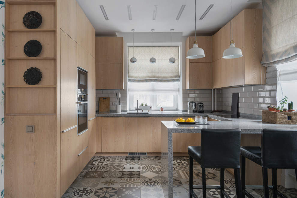 Mid-sized scandinavian u-shaped eat-in kitchen in Moscow with an undermount sink, flat-panel cabinets, medium wood cabinets, solid surface benchtops, white splashback, ceramic splashback, stainless steel appliances, ceramic floors, with island, brown floor, grey benchtop and recessed.