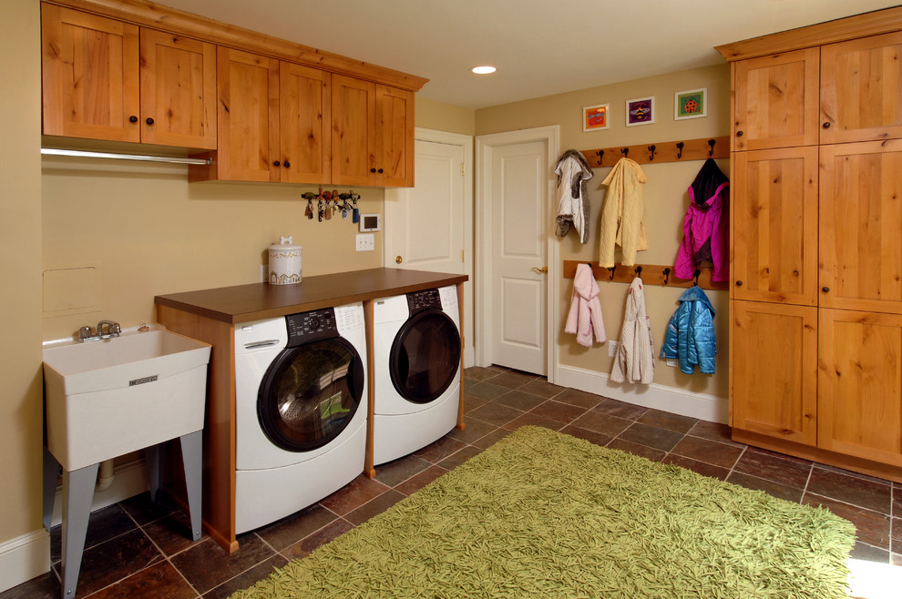 This is an example of a large traditional utility room in DC Metro with an utility sink, shaker cabinets, medium wood cabinets, laminate benchtops, ceramic floors, a side-by-side washer and dryer, brown floor, brown benchtop and beige walls.