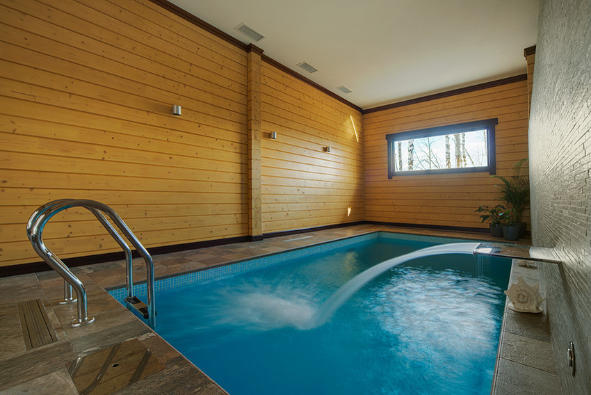This is an example of a mid-sized indoor rectangular infinity pool in Other with a hot tub and tile.