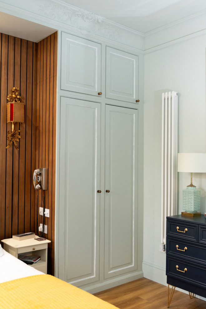 Modelo de dormitorio principal clásico de tamaño medio con paredes azules, suelo de madera en tonos medios, suelo marrón y panelado
