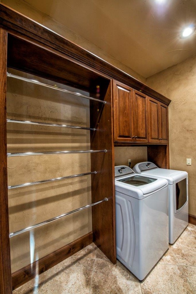 Inspiration for a mid-sized traditional single-wall dedicated laundry room in Other with raised-panel cabinets, dark wood cabinets, beige walls, porcelain floors and a side-by-side washer and dryer.