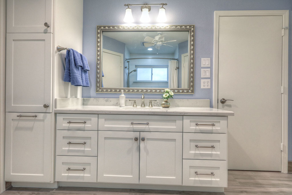 Inspiration for a large traditional master bathroom in Houston with shaker cabinets, white cabinets, an alcove tub, a shower/bathtub combo, white tile, porcelain tile, blue walls, medium hardwood floors, an undermount sink, marble benchtops, brown floor and a shower curtain.