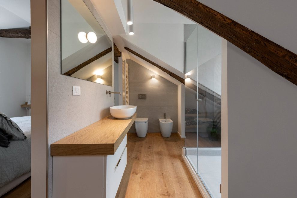 Foto på ett litet skandinaviskt badrum med dusch, med skåp i ljust trä, en hörndusch, en toalettstol med separat cisternkåpa, porslinskakel, laminatgolv, ett fristående handfat, träbänkskiva och dusch med gångjärnsdörr