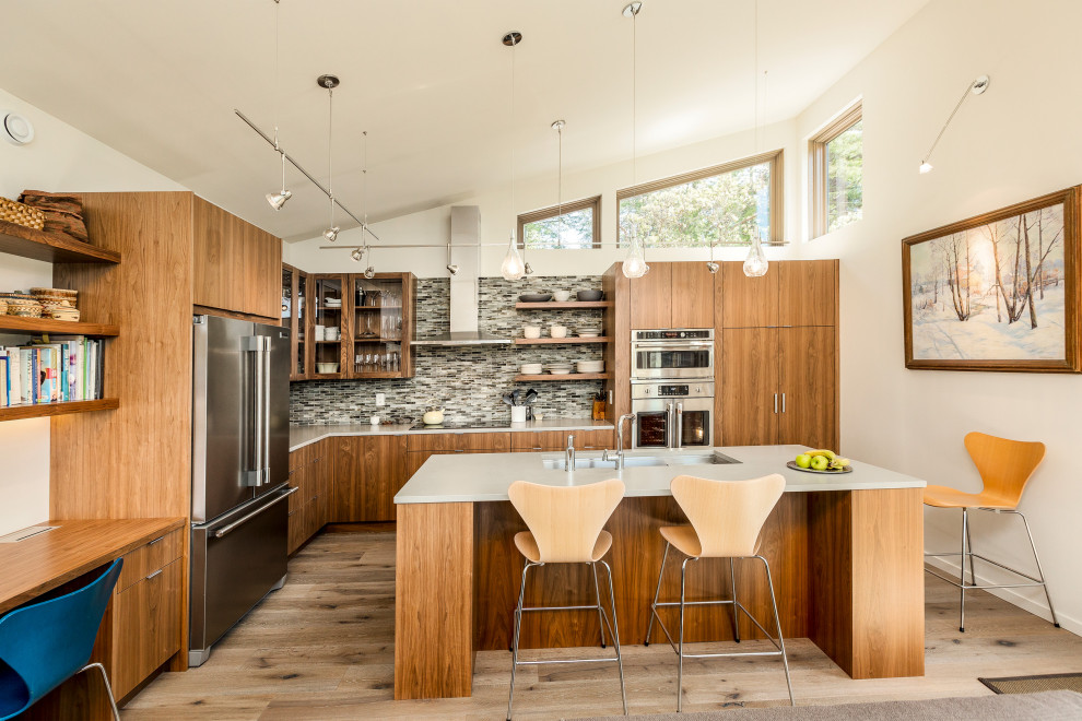 Inspiration for a large midcentury l-shaped open plan kitchen in Seattle with an undermount sink, flat-panel cabinets, medium wood cabinets, quartz benchtops, multi-coloured splashback, glass tile splashback, stainless steel appliances, medium hardwood floors, with island, brown floor and white benchtop.