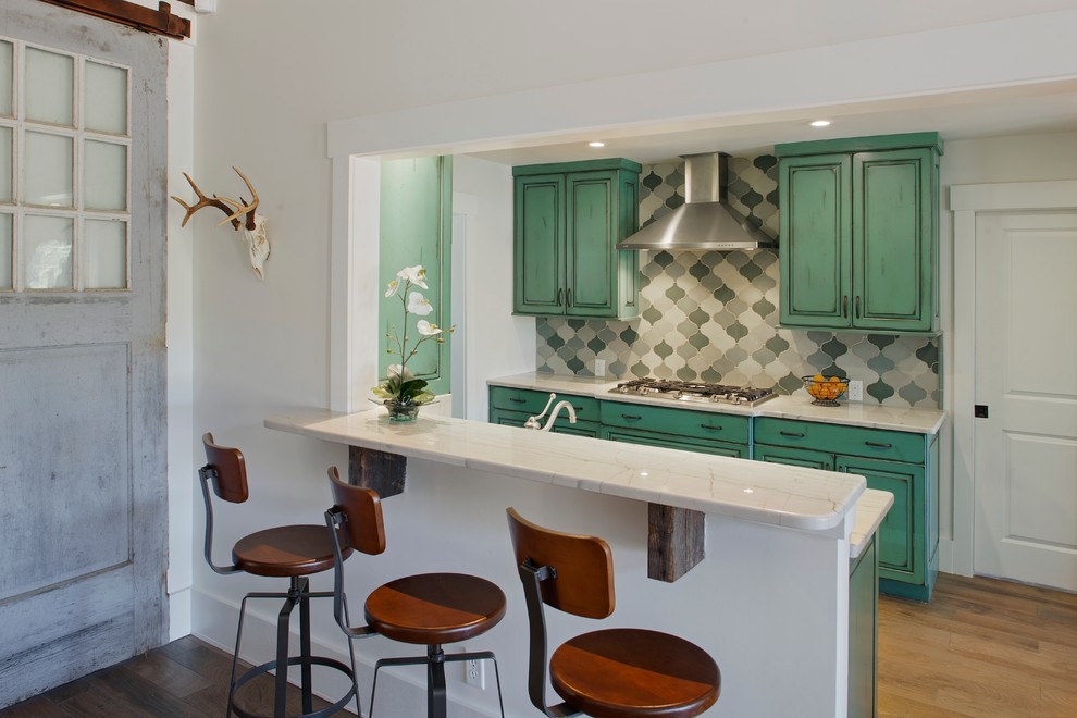 Eclectic eat-in kitchen in Atlanta with a farmhouse sink, raised-panel cabinets, blue cabinets, marble benchtops, grey splashback, stone slab splashback and stainless steel appliances.