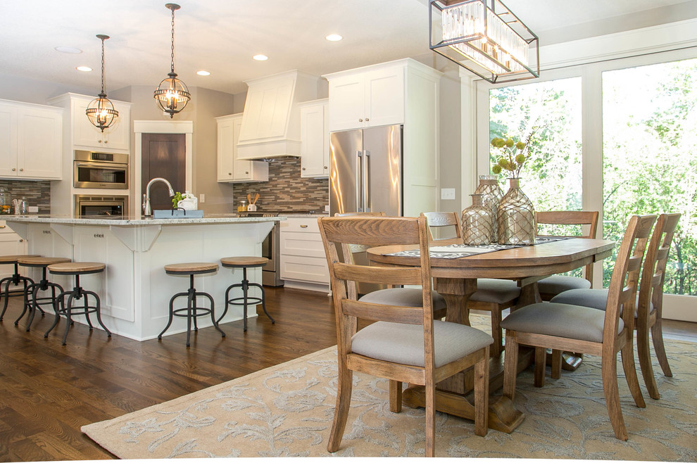 Example of a transitional l-shaped medium tone wood floor eat-in kitchen design in Minneapolis with a drop-in sink, recessed-panel cabinets, white cabinets, granite countertops, multicolored backsplash, glass tile backsplash, stainless steel appliances and an island