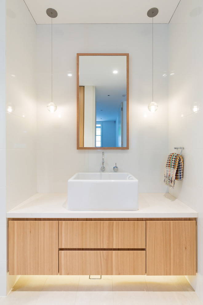 Contemporary bathroom in Sydney with light wood cabinets, white tile, ceramic tile, ceramic floors, solid surface benchtops, white benchtops, flat-panel cabinets, white walls, a vessel sink and beige floor.