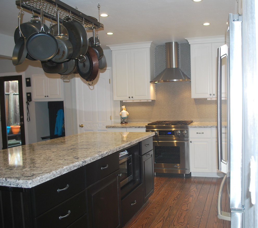 Exempel på ett mellanstort klassiskt kök, med en undermonterad diskho, luckor med upphöjd panel, bänkskiva i kvarts, grått stänkskydd, glaspanel som stänkskydd, rostfria vitvaror, mörkt trägolv och en köksö