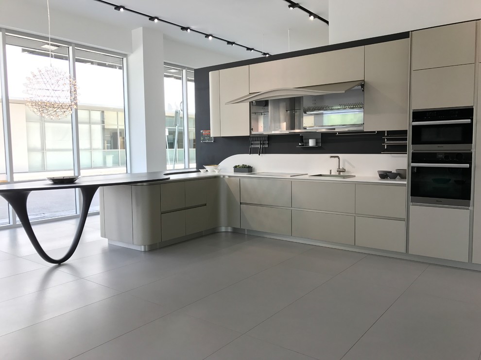 Photo of a large contemporary l-shaped eat-in kitchen in Houston with a single-bowl sink, flat-panel cabinets, beige cabinets, quartz benchtops, white splashback, stone slab splashback, stainless steel appliances, ceramic floors, a peninsula, grey floor and white benchtop.
