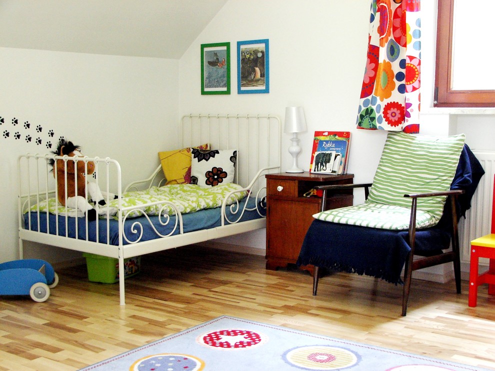 Photo of a transitional kids' room for girls in Other with white walls and light hardwood floors.