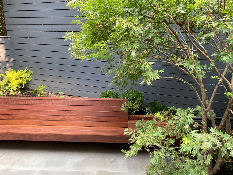 На фото: тенистый, осенний участок и сад на заднем дворе в стиле ретро с покрытием из каменной брусчатки и с деревянным забором