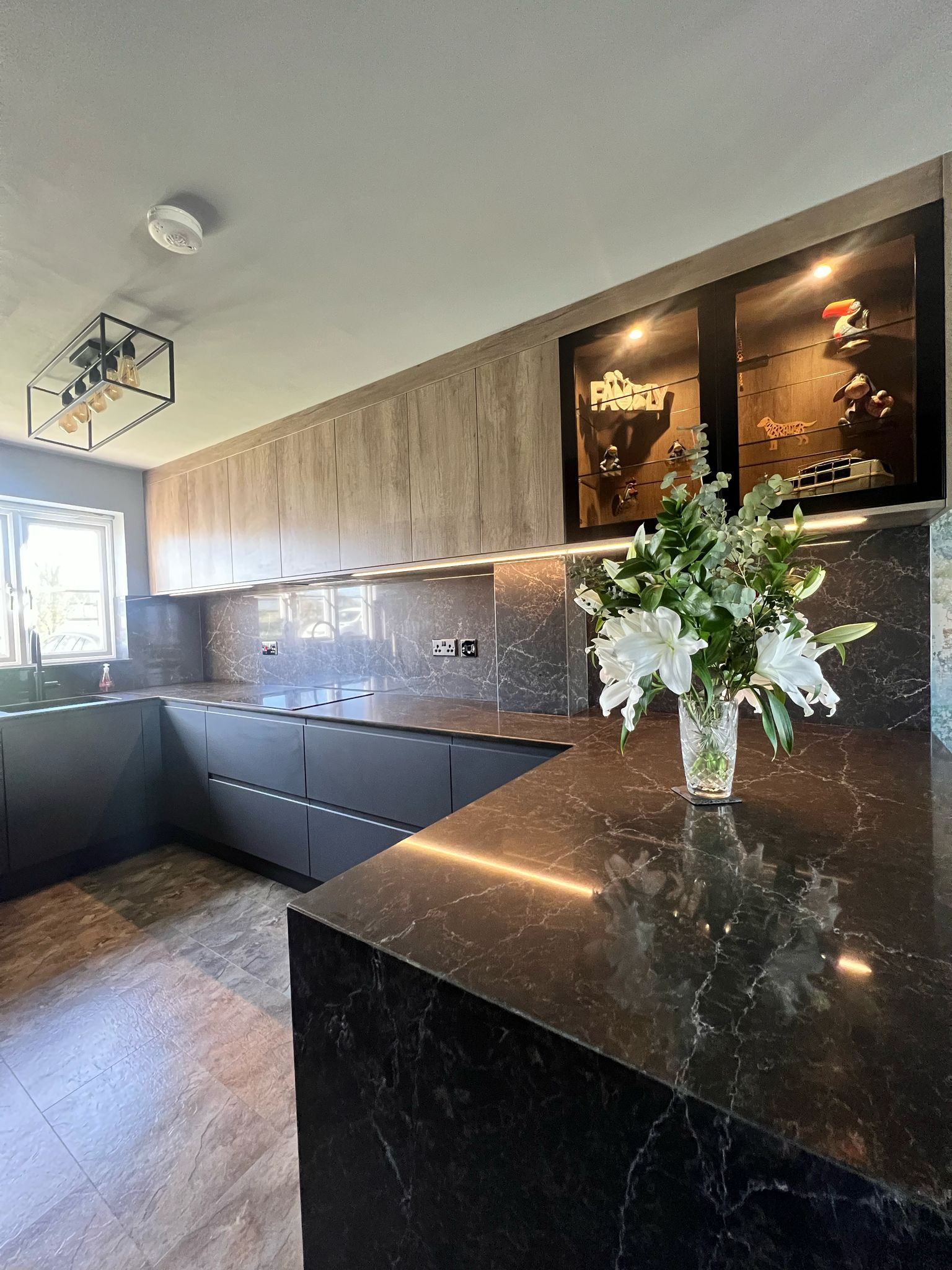 Inspiration for a mid-sized contemporary u-shaped vinyl floor and brown floor eat-in kitchen remodel in Other with a drop-in sink, flat-panel cabinets, dark wood cabinets, quartzite countertops, brown