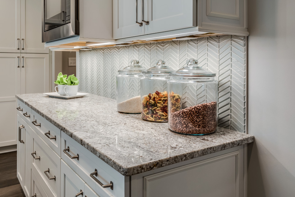 Inspiration for a mid-sized transitional l-shaped open concept kitchen remodel with an undermount sink, flat-panel cabinets, white cabinets, quartz countertops, white backsplash, glass tile backsplash, stainless steel appliances, an island and white countertops