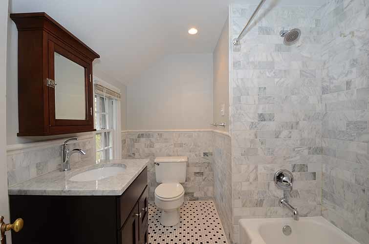 Inspiration for a mid-sized traditional 3/4 bathroom in Philadelphia with shaker cabinets, dark wood cabinets, an alcove tub, a shower/bathtub combo, a two-piece toilet, stone tile, white walls, mosaic tile floors, an undermount sink and marble benchtops.