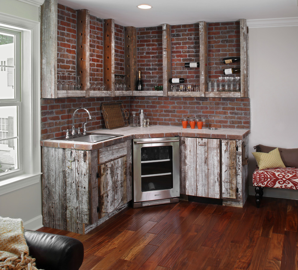 This is an example of a traditional home bar in Jacksonville with tile benchtops, red splashback and dark hardwood floors.