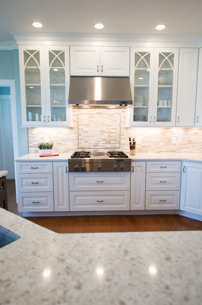 Example of a transitional l-shaped medium tone wood floor eat-in kitchen design in Boston with white cabinets, granite countertops, gray backsplash, stainless steel appliances and an island