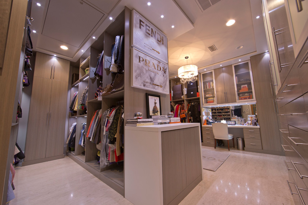 Expansive modern women's dressing room in New Orleans with flat-panel cabinets, grey cabinets and travertine floors.
