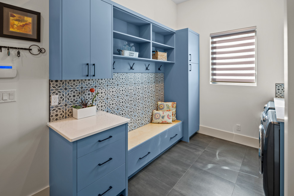 Photo of a contemporary galley utility room in Vancouver with an undermount sink, flat-panel cabinets, blue cabinets, quartz benchtops, blue splashback, ceramic splashback, white walls, ceramic floors, a side-by-side washer and dryer, grey floor and yellow benchtop.