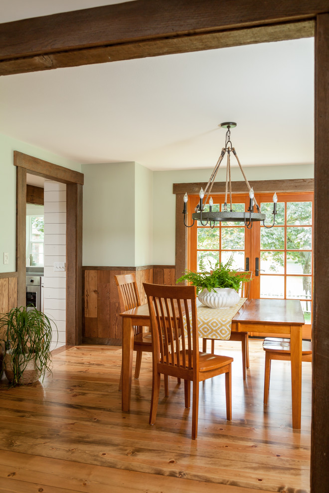 Mid-sized country medium tone wood floor, brown floor and wainscoting enclosed dining room photo in Seattle with green walls