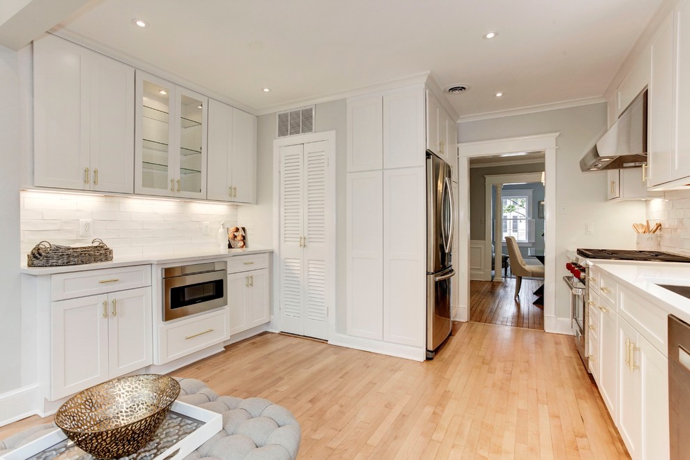 Kitchen - transitional light wood floor kitchen idea in DC Metro with shaker cabinets, white cabinets, quartz countertops, white backsplash, ceramic backsplash, stainless steel appliances and white countertops