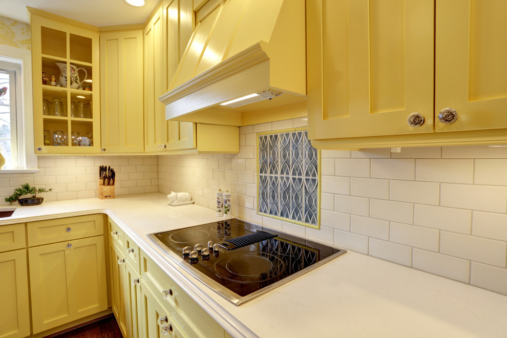 Inspiration for an arts and crafts l-shaped kitchen in DC Metro with a farmhouse sink, recessed-panel cabinets, yellow cabinets, quartzite benchtops, white splashback, subway tile splashback, stainless steel appliances, medium hardwood floors and no island.