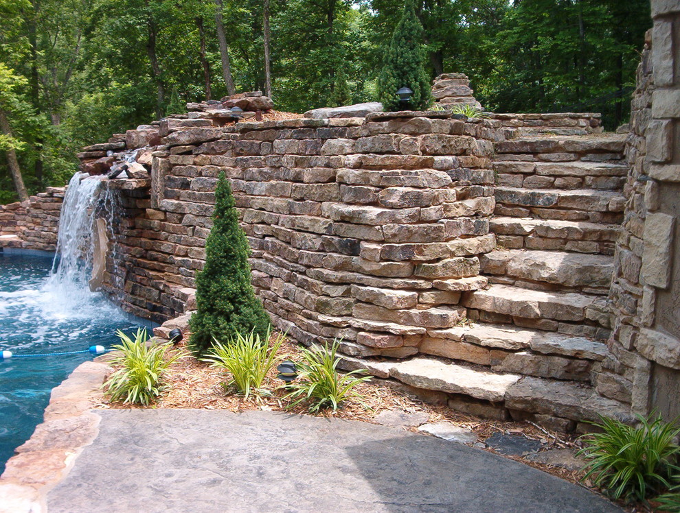 Large country backyard custom-shaped natural pool in Other with a water slide and stamped concrete.
