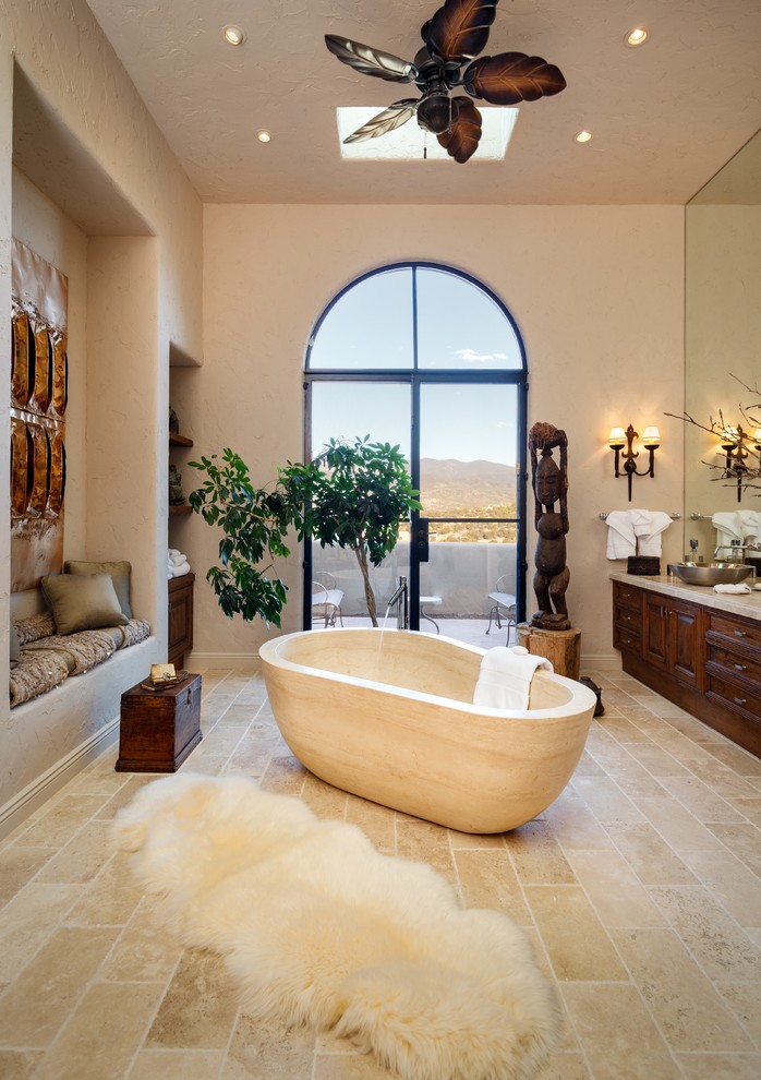 Inspiration for a large transitional master beige tile, white tile and stone tile ceramic tile and beige floor freestanding bathtub remodel in Albuquerque with raised-panel cabinets, dark wood cabinets, a one-piece toilet, beige walls, a pedestal sink and soapstone countertops