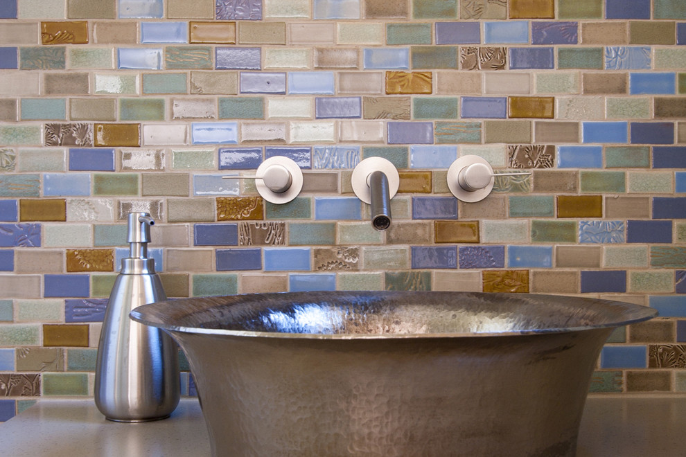 This is an example of a mid-sized beach style 3/4 bathroom in Minneapolis with a vessel sink, flat-panel cabinets, light wood cabinets, a one-piece toilet, multi-coloured tile, ceramic tile, beige walls and ceramic floors.