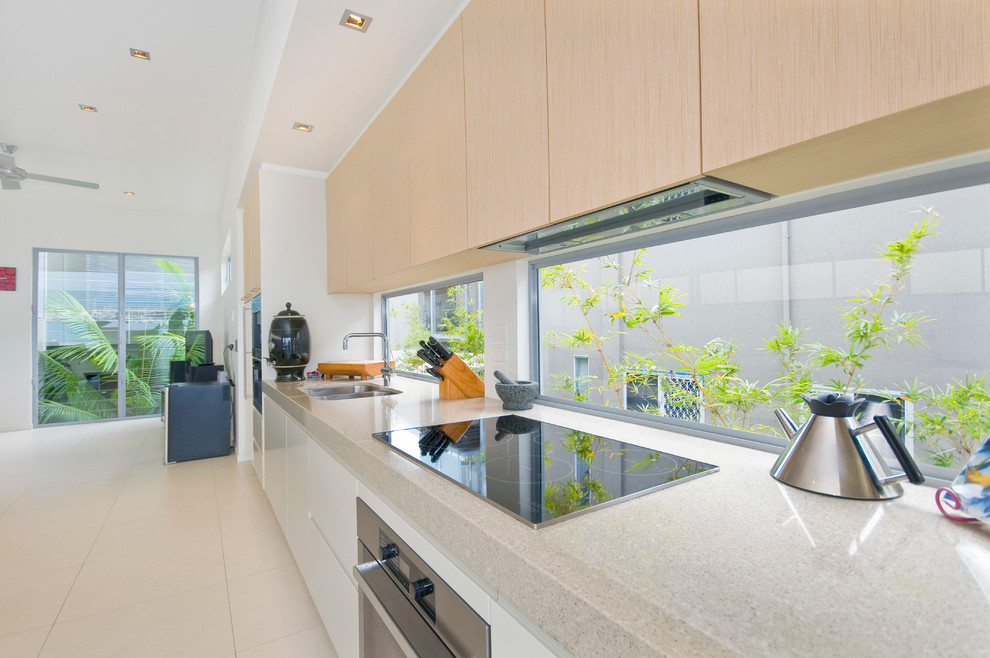 Photo of a mid-sized contemporary galley eat-in kitchen in Brisbane with an undermount sink, quartz benchtops, multi-coloured splashback, glass sheet splashback, stainless steel appliances, porcelain floors and with island.