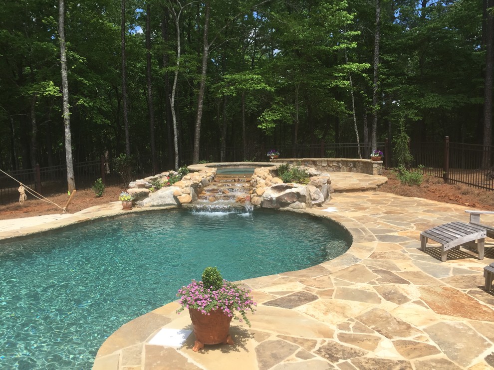 Mid-sized country backyard custom-shaped natural pool in Atlanta with a hot tub and natural stone pavers.
