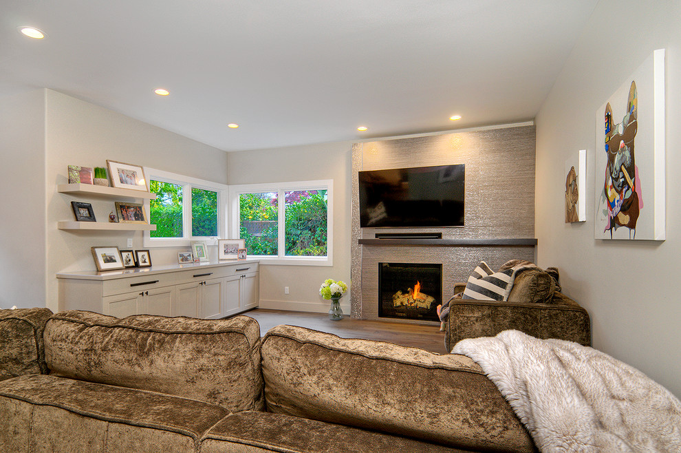 Photo of a mid-sized transitional open concept living room in San Francisco with grey walls, medium hardwood floors, a standard fireplace, a tile fireplace surround, a wall-mounted tv and grey floor.