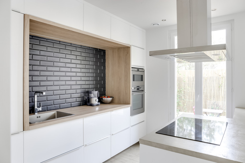 Design ideas for a contemporary galley eat-in kitchen in Marseille with concrete benchtops, black splashback, subway tile splashback, stainless steel appliances, ceramic floors, with island, an undermount sink, white cabinets and beige benchtop.