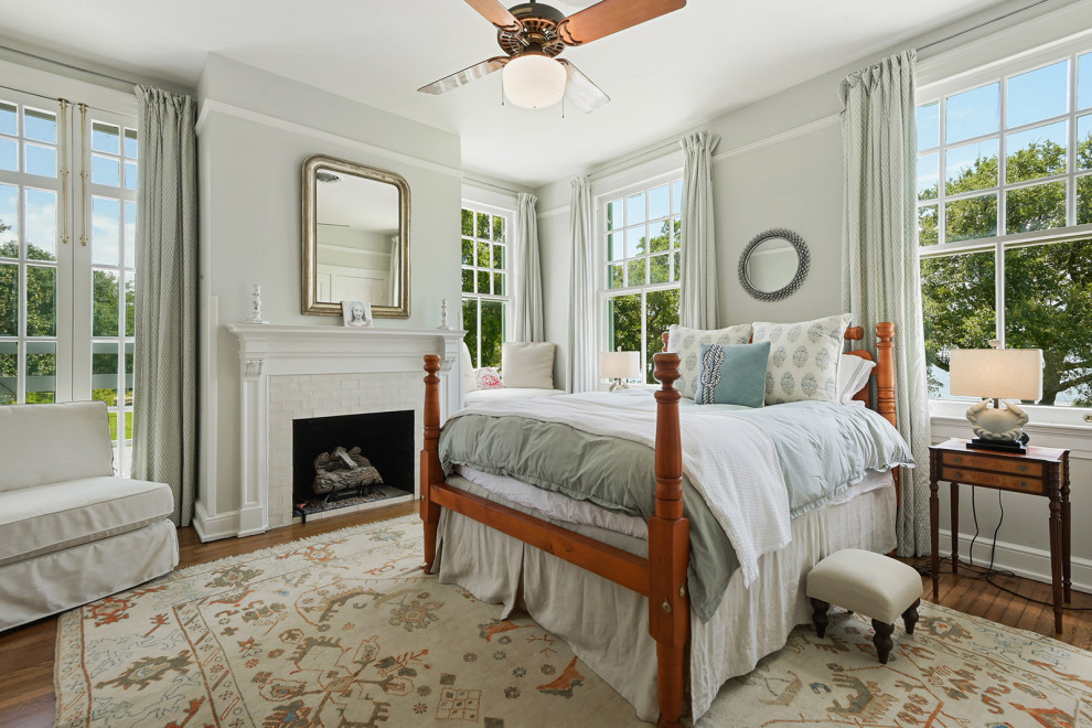 На фото: гостевая спальня среднего размера, (комната для гостей) в классическом стиле с серыми стенами, паркетным полом среднего тона, стандартным камином, фасадом камина из плитки и коричневым полом