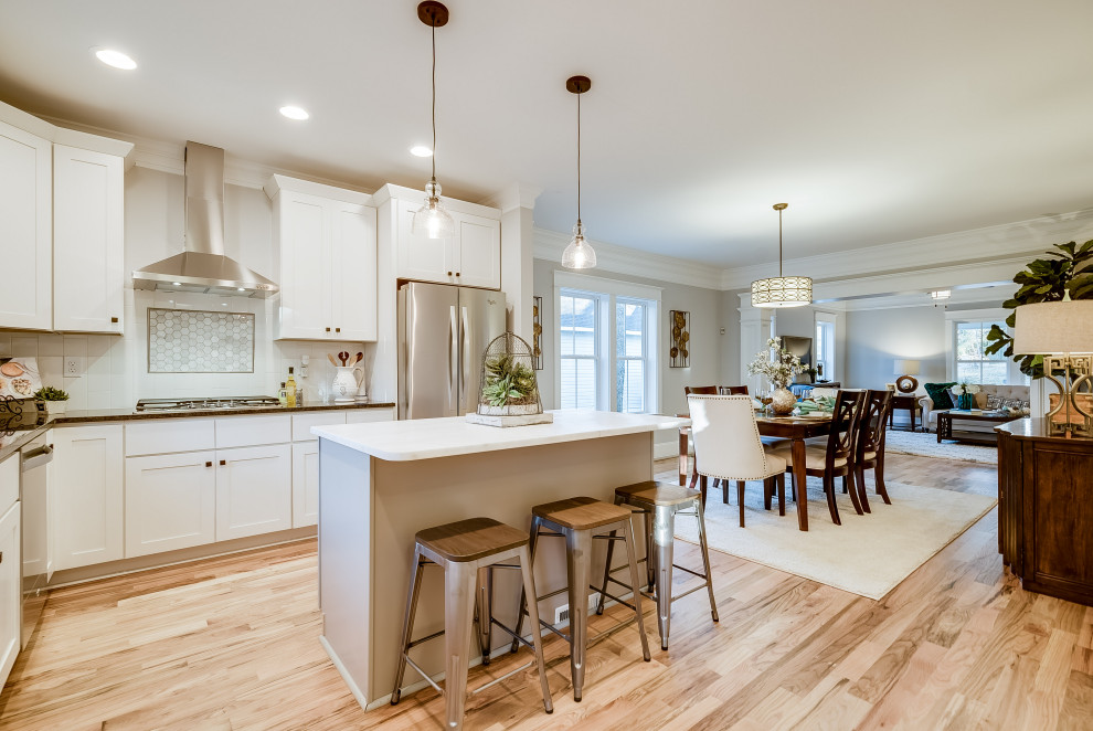 Mid-sized arts and crafts u-shaped kitchen pantry in Raleigh with an undermount sink, shaker cabinets, white cabinets, granite benchtops, yellow splashback, subway tile splashback, stainless steel appliances, light hardwood floors and with island.