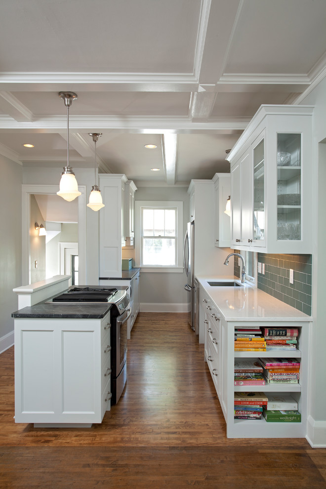 Inspiration for a small arts and crafts galley open plan kitchen in Minneapolis with a single-bowl sink, recessed-panel cabinets, grey cabinets, soapstone benchtops, green splashback, glass tile splashback, stainless steel appliances, medium hardwood floors, with island and beige floor.