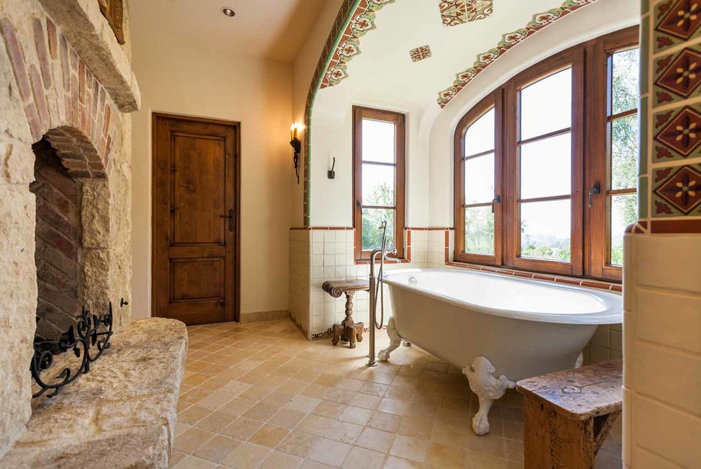 Design ideas for a mediterranean master bathroom in San Diego with a claw-foot tub, beige tile, beige walls and beige floor.