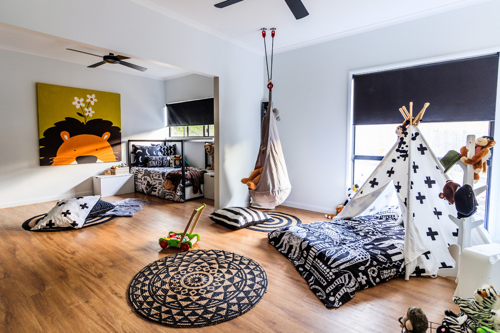 This is an example of a large modern gender-neutral kids' room in Sunshine Coast with vinyl floors, white walls and brown floor.