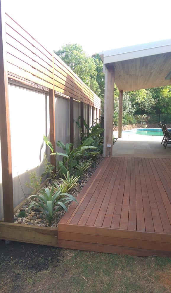 Design ideas for a mid-sized tropical backyard deck in Brisbane with a roof extension.