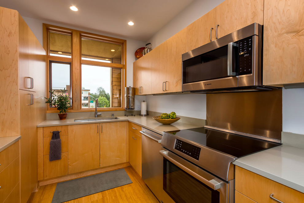 Design ideas for a mid-sized modern galley open plan kitchen in Seattle with an undermount sink, flat-panel cabinets, light wood cabinets, quartzite benchtops, grey splashback, stone slab splashback, stainless steel appliances, bamboo floors, no island and grey benchtop.
