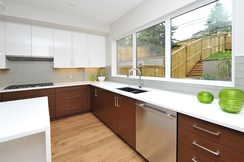 Large transitional l-shaped medium tone wood floor eat-in kitchen photo in Calgary with an undermount sink, flat-panel cabinets, medium tone wood cabinets, gray backsplash, stainless steel appliances and an island