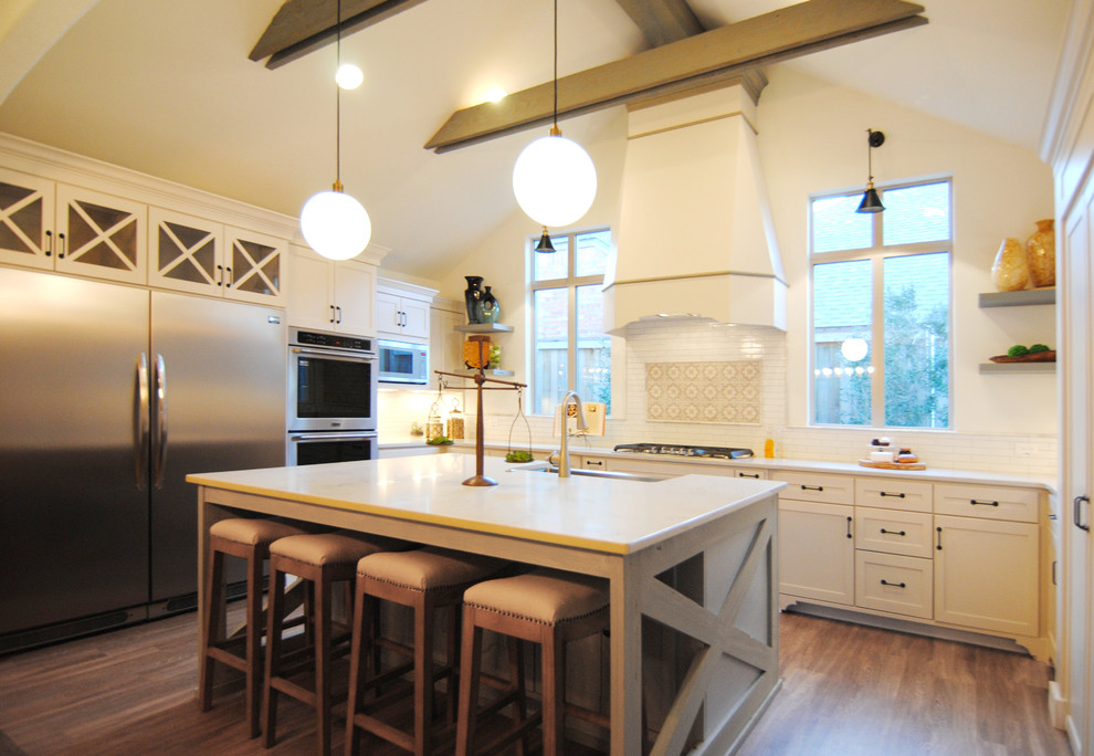 This is an example of a large contemporary u-shaped eat-in kitchen in Austin with a farmhouse sink, shaker cabinets, white cabinets, quartzite benchtops, white splashback, subway tile splashback, stainless steel appliances, vinyl floors and with island.