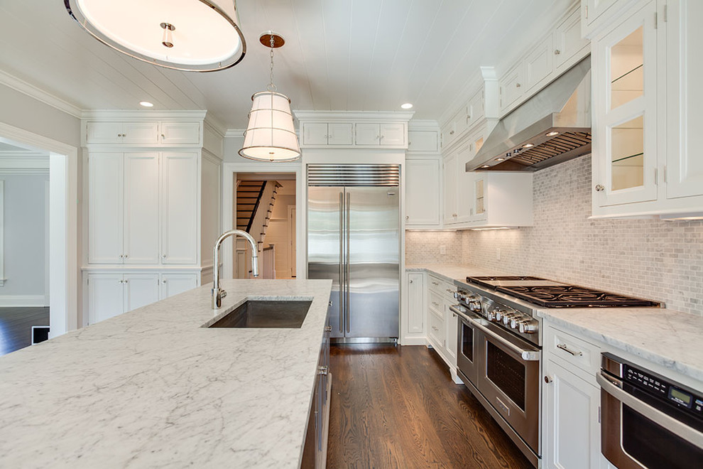 Example of a mid-sized transitional l-shaped dark wood floor and brown floor eat-in kitchen design with an undermount sink, recessed-panel cabinets, white cabinets, white backsplash, stainless steel appliances, an island and marble countertops