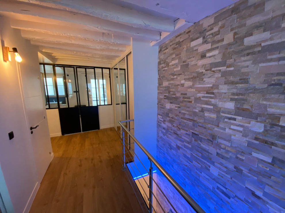 На фото: огромный коридор в современном стиле с бежевыми стенами, светлым паркетным полом, бежевым полом, балками на потолке и кирпичными стенами с