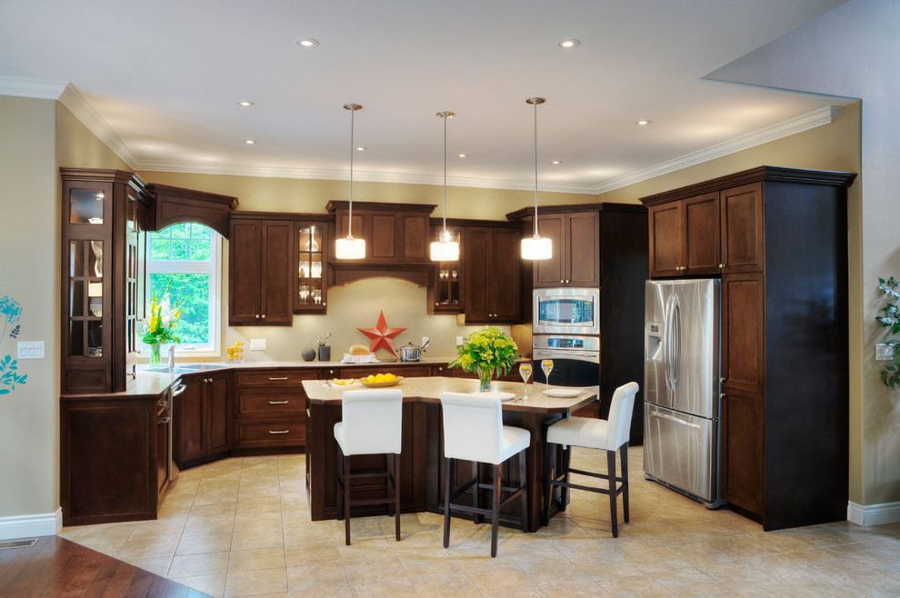 This is an example of a large transitional u-shaped eat-in kitchen in Other with a drop-in sink, shaker cabinets, dark wood cabinets, laminate benchtops, stainless steel appliances, travertine floors and with island.