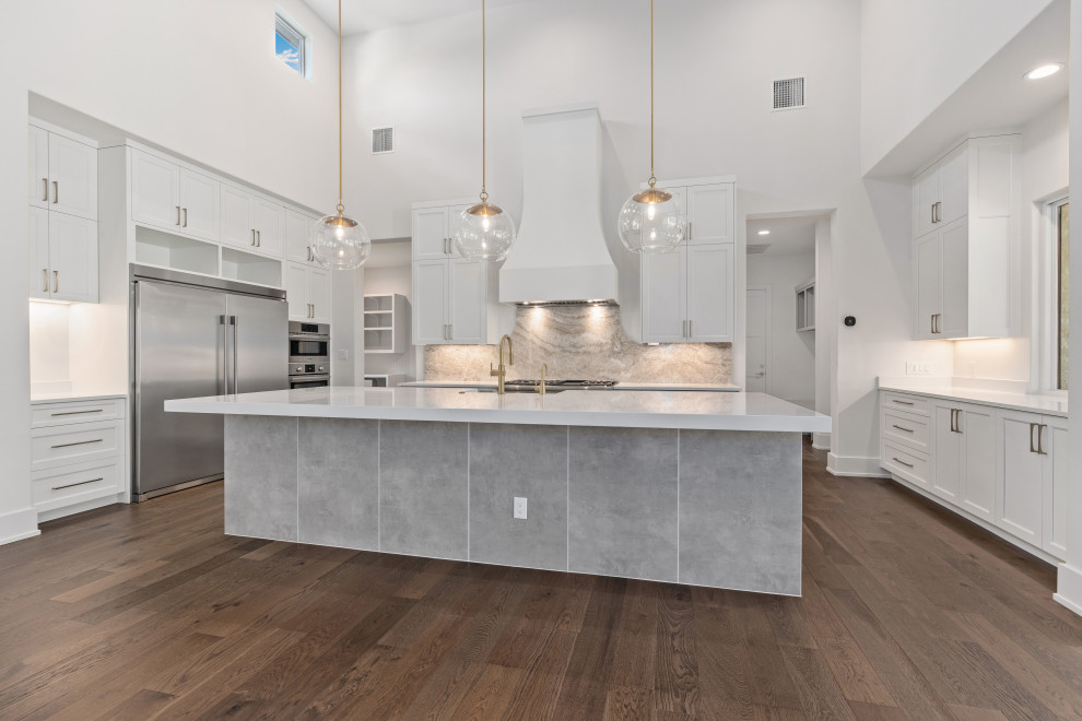 Open concept kitchen - large transitional medium tone wood floor and brown floor open concept kitchen idea with gray backsplash, granite backsplash, stainless steel appliances, an island and white countertops