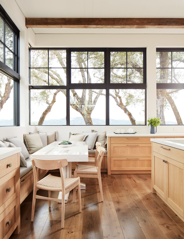 This is an example of a country eat-in kitchen in San Francisco with shaker cabinets, light wood cabinets, medium hardwood floors and white benchtop.