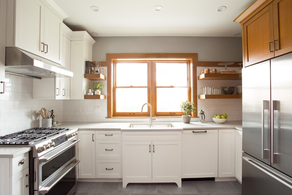 Inspiration for an arts and crafts u-shaped kitchen in Chicago with an undermount sink, shaker cabinets, white cabinets, solid surface benchtops, white splashback, porcelain splashback, stainless steel appliances, grey floor and grey benchtop.