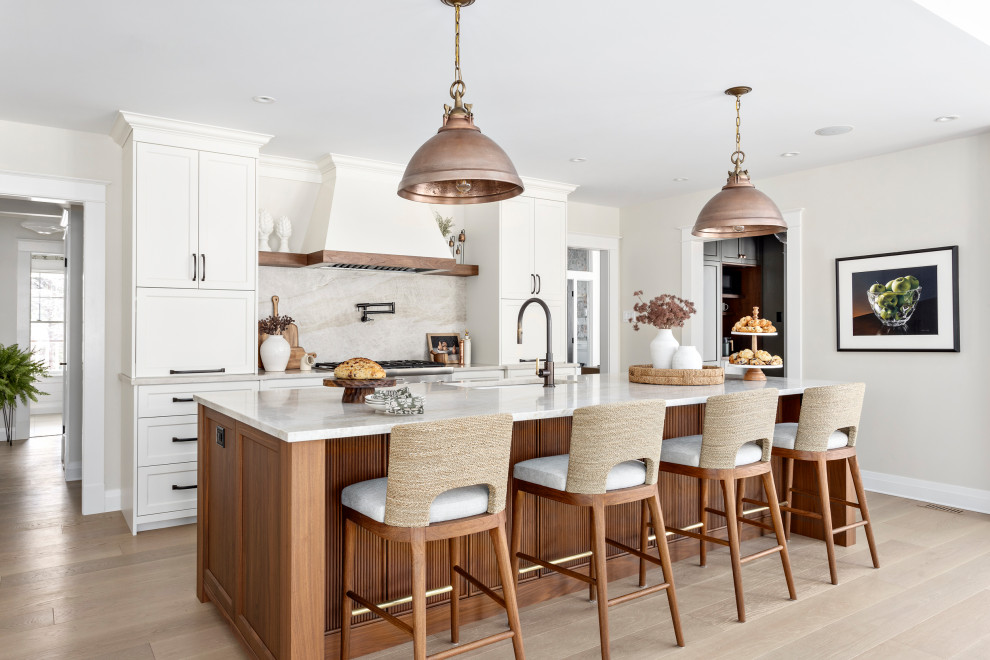 Inspiration for a large transitional light wood floor and beige floor open concept kitchen remodel in Other with an undermount sink, shaker cabinets, quartz countertops, quartz backsplash, stainless steel appliances, an island, beige countertops, white cabinets and beige backsplash